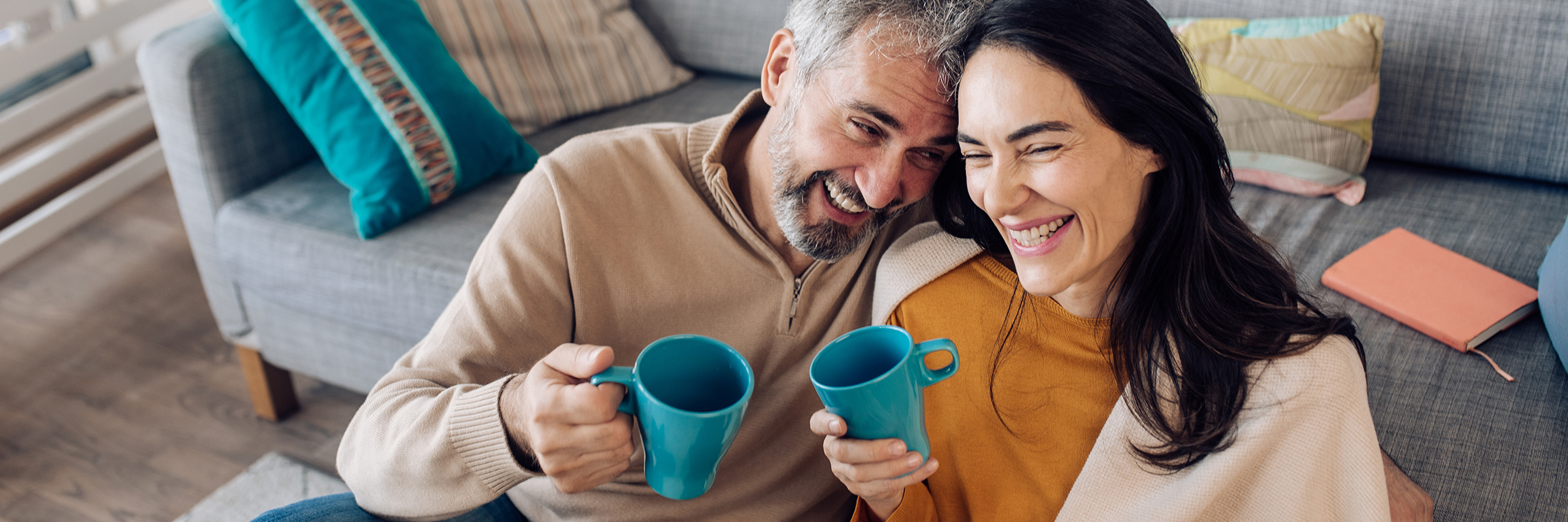 Couple in their home smiling and drinking coffee